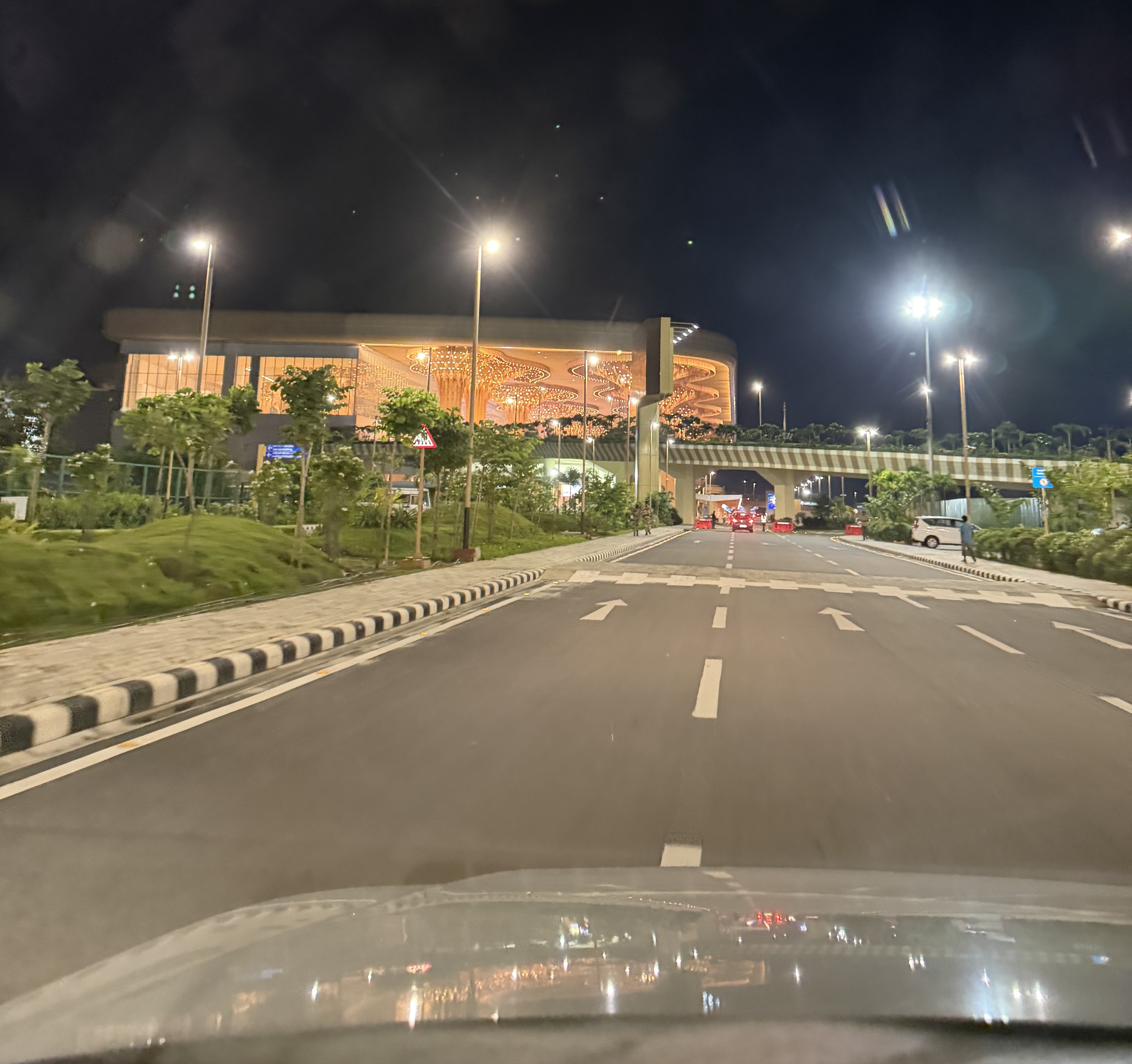 an airport terminal lit up at night, seen from inside a car